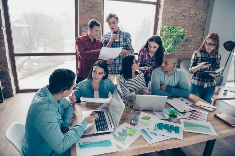 Jovens executivos debatem numa sala planilhas e números de uma organização.