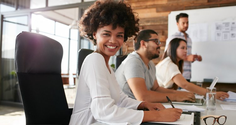 executiva sorridente sentada à mesa de reunião com outros colegas de trabalho